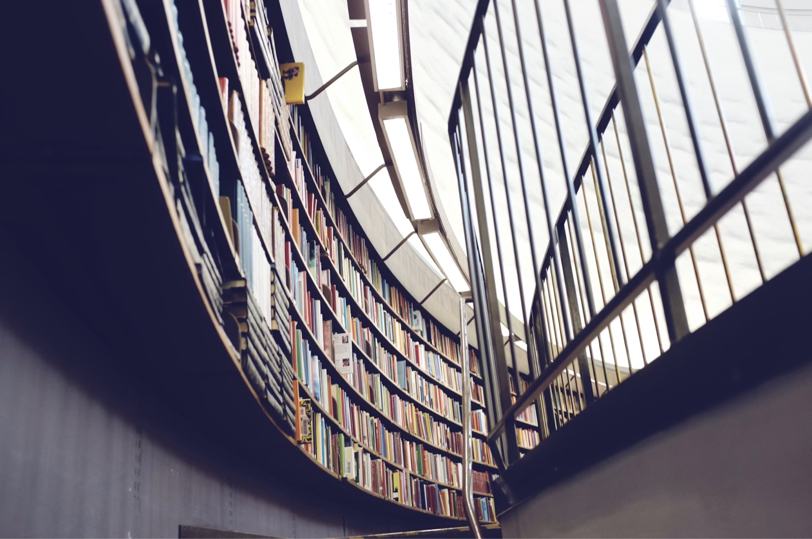 The sweeping curved balconies of a public library, tiers of book-lined shelves following the wall around a bright central atrium.